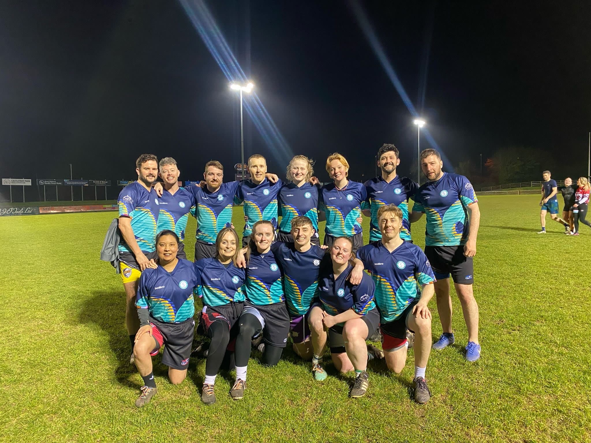 Sarsfields Rugby players gathered together on a floodlit pitch