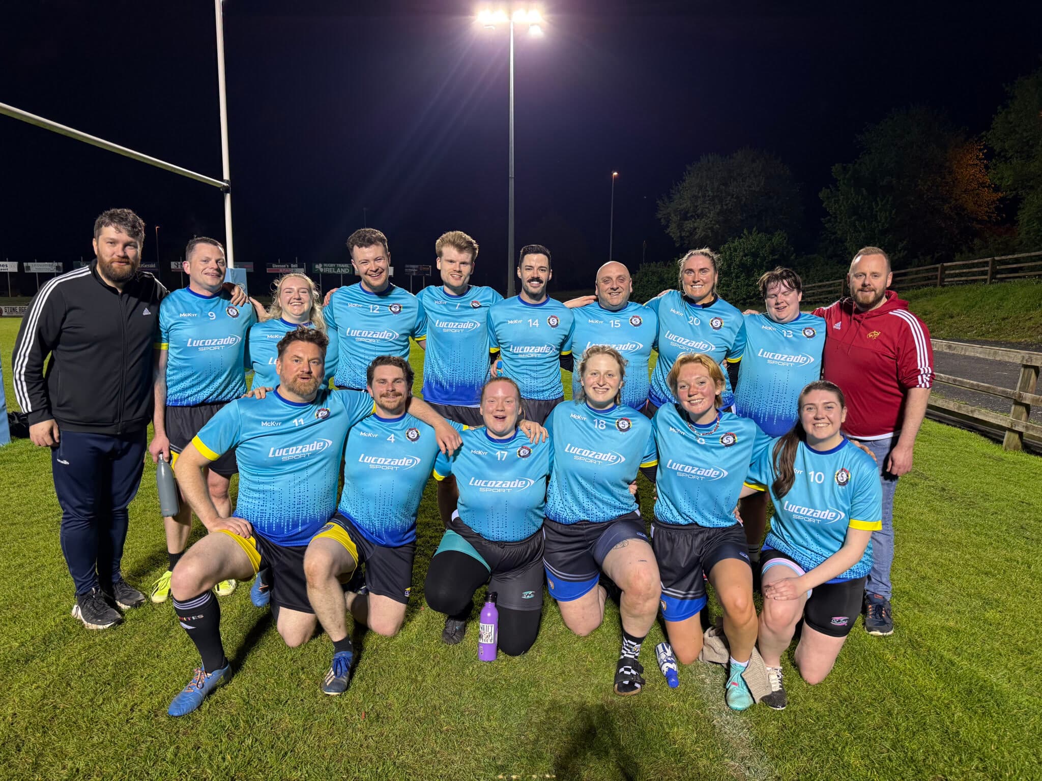 Sarsfields Rugby players and coaches together after a match under floodlights